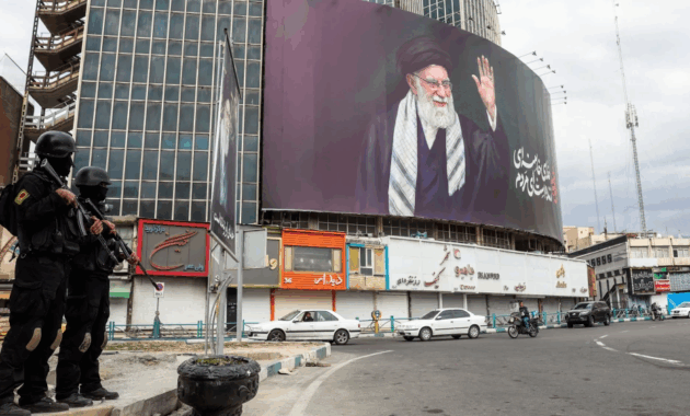 Miembros de las fuerzas de seguridad iraníes vigilan en una calle junto a una valla publicitaria del líder supremo iraní, el ayatolá Ali Jamenei, en Teherán el 2 de marzo de 2026.Foto: AFP.