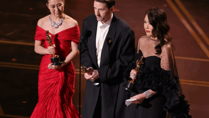Maggie Kang, Chris Appelhans y Michelle L.M. Wong subieron para recibir el premio de Mejor Animación otorgado a la película Las Guerreras K-Pop.Foto: AFP.