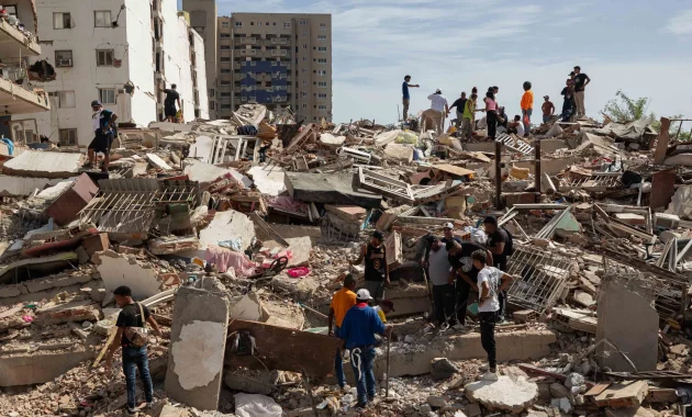 Personas caminan entre escombros de edificios afectado por terremotos este jueves, en Catia La Mar (Venezuela). Foto: Ronald Peña R./EFE.